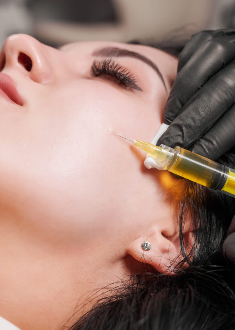 Close-up of plasmolifting procedure injection. Doctor cosmetologist beautician in black sterile gloves making injection in female patient face. Concept of skincare treatment.